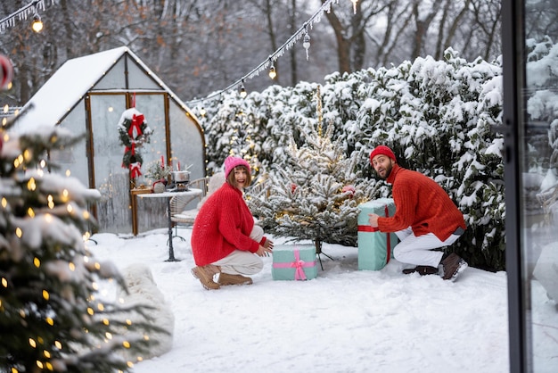 Le jeune couple décore l'arbre de Noël à l'arrière-cour