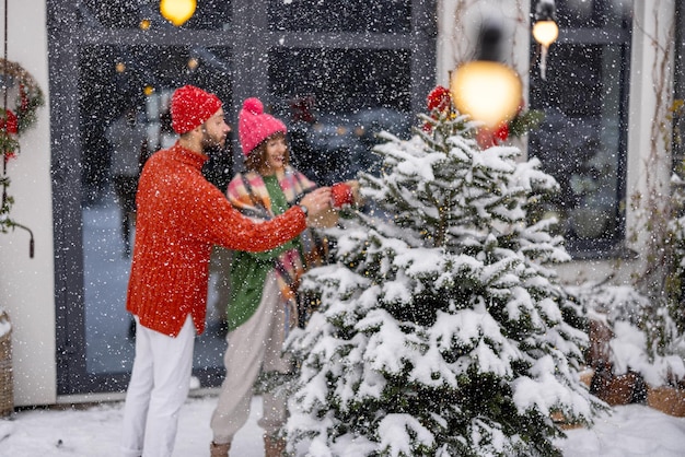 Un jeune couple décore un arbre de Noël dans la cour