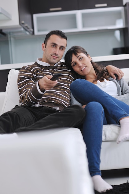 Jeune couple détendu regardant la télévision à la maison dans un salon lumineux