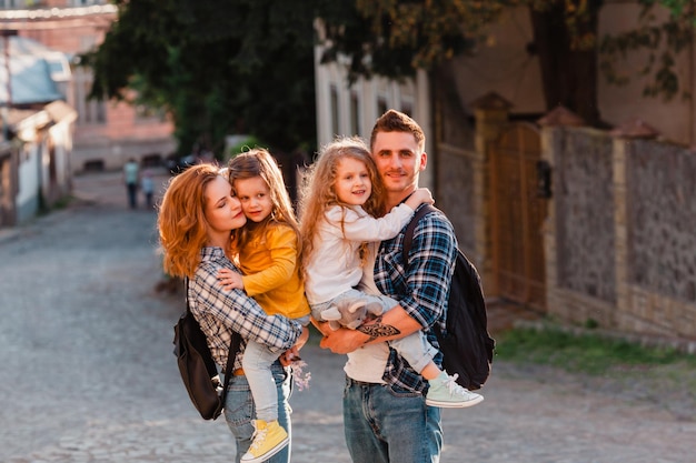 Le jeune couple avec deux filles parcourt les rues de la vieille ville Papa et maman tiennent leurs enfants dans leurs bras