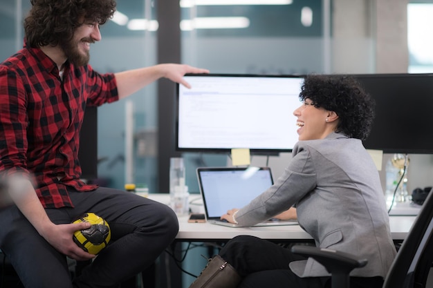 jeune couple de développeurs de logiciels utilisant un ordinateur portable et un ordinateur de bureau tout en écrivant du code de programmation dans un bureau de démarrage créatif moderne