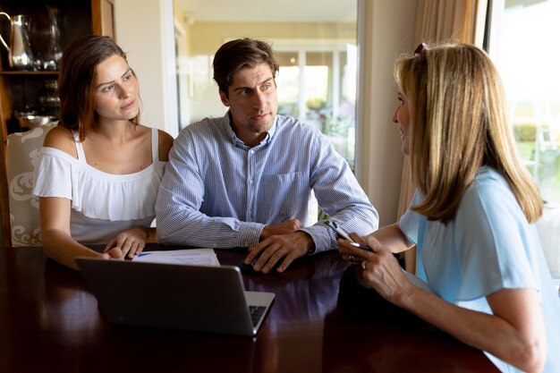 Photo un jeune couple discute avec un conseiller financier à la maison.