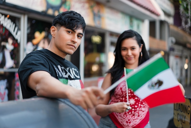 Photo jeune couple avec des drapeaux mexicains dans la rue