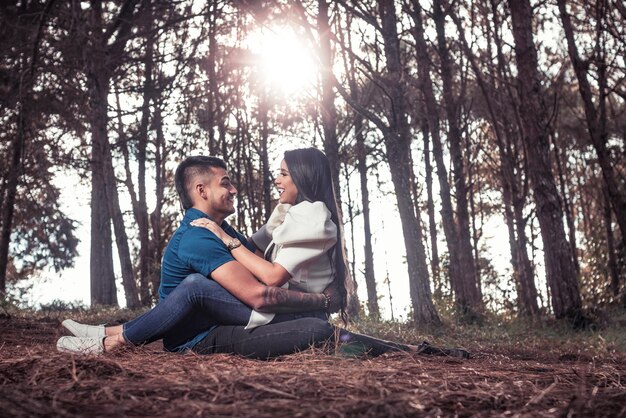 Photo jeune couple embrassant amoureusement contre la lumière dans une forêt de pins