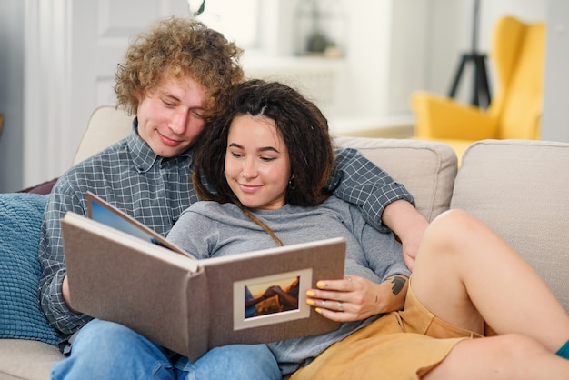 Jeune couple enceinte attendant un bébé et regardant son livre photo de famille