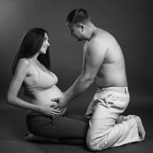 Jeune couple enceinte étreignant et souriant. L'amour et la tendresse. En attente d'un miracle. Portrait noir et blanc