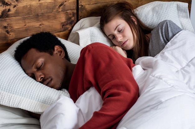 Jeune couple endormi dans un lit.