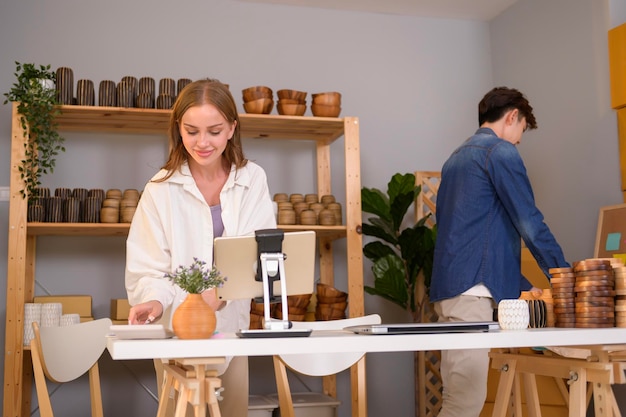 Un jeune couple entrepreneur vérifiant et emballant des produits artisanaux vendus aux clients dans leur boutique