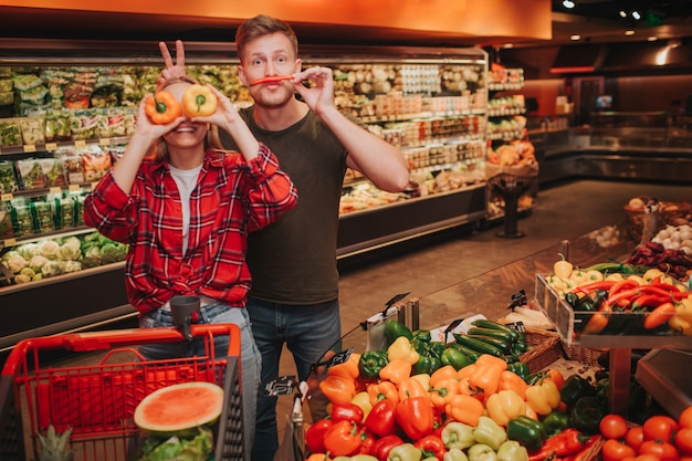 Jeune couple en épicerie jouant avec des légumes