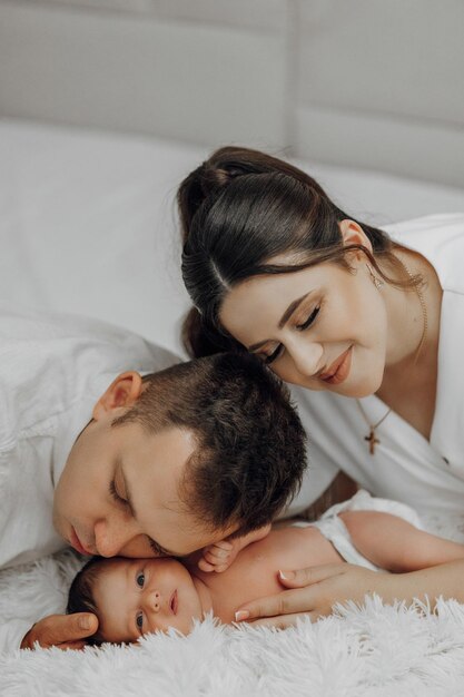 Un jeune couple est allongé sur un lit avec leur bébé.