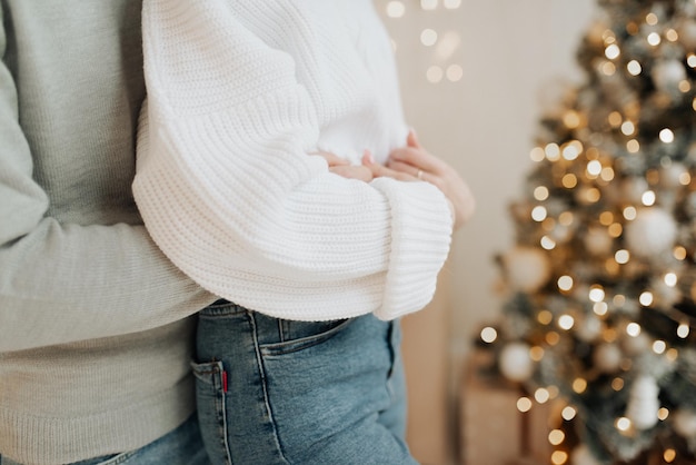 Jeune couple étreignant sur le fond de l'arbre de Noël