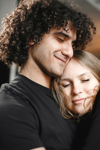 Jeune couple étreignant les yeux fermés.