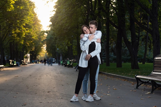 Jeune couple étreint dans le parc Guy embrasse doucement sa petite amie par derrière