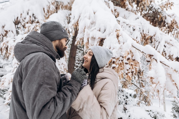 Un jeune couple étreint posant s'embrassant s'amusant en hiver saison enneigée dans le parc de la ville