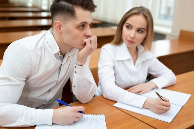 Jeune couple d'étudiants un gars et une fille assis à un bureau lors d'une conférence et se tenir la main