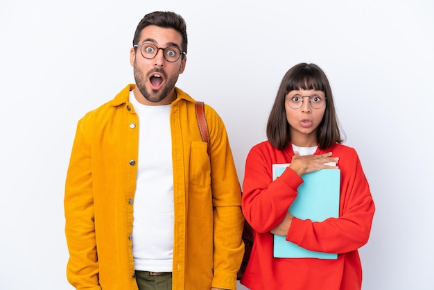 Jeune couple d'étudiants isolé sur fond blanc avec une expression faciale surprise et choquée