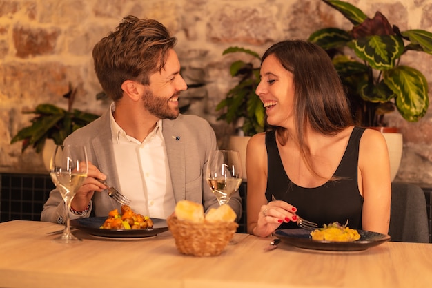 Un jeune couple européen dans un restaurant, s'amusant en train de dîner avec de la nourriture, célébrant la Saint-Valentin