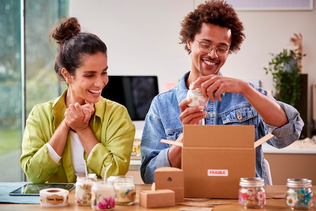 Photo jeune couple exécutant des affaires en ligne à partir de la maison emballant des bougies de boutique prêtes pour l'expédition