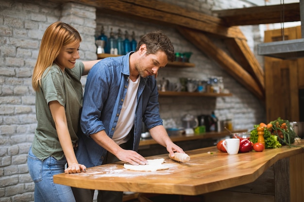 Jeune couple, faire, pizza, dans, cuisine rustique, ensemble