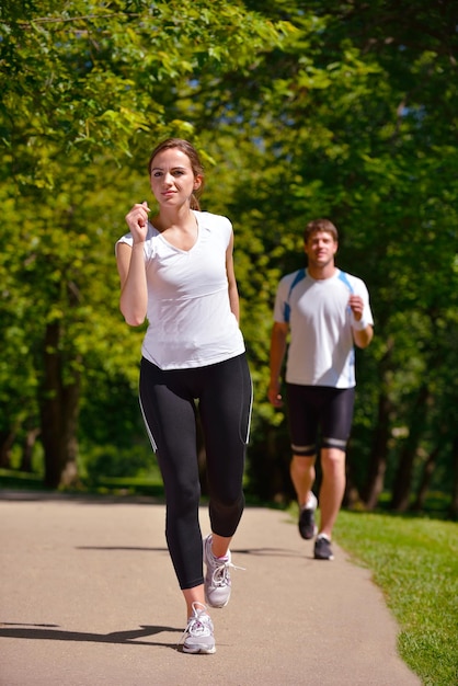 Photo jeune couple faisant du jogging dans le parc le matin. santé et remise en forme.