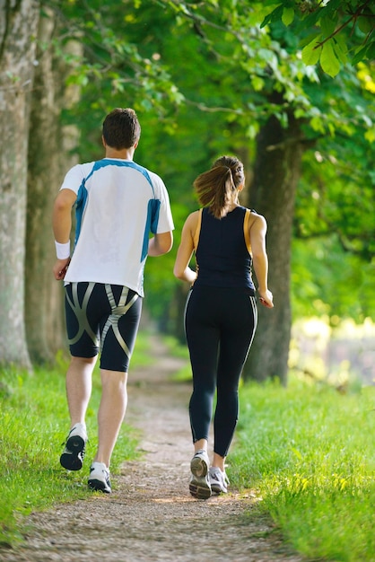 Photo jeune couple faisant du jogging dans le parc le matin. santé et remise en forme.