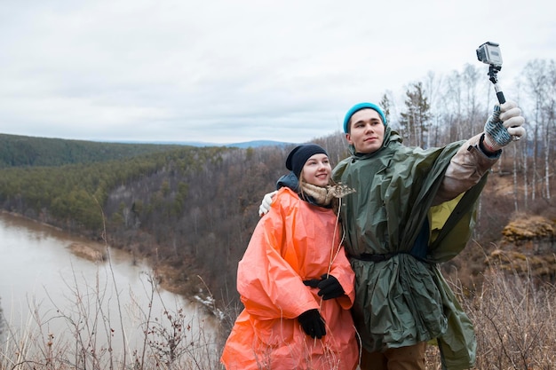 Jeune couple faisant du selfie à flanc de colline jusqu'à la rivière