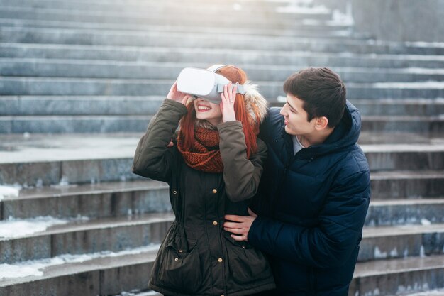 Jeune couple faisant l'expérience de la réalité virtuelle (VR) dans la rue