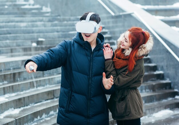 Jeune couple faisant l'expérience de la réalité virtuelle (VR) dans la rue