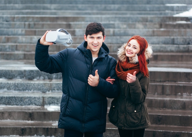 Jeune couple faisant l'expérience de la réalité virtuelle (VR) dans la rue