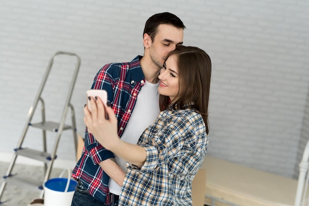 Un jeune couple fait un selfie en emménageant dans un nouvel appartement. Déménagement des jeunes mariés dans un nouveau logement.