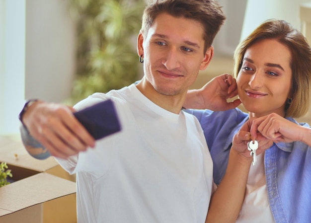 Un jeune couple fait un selfie en emménageant dans un nouvel appartement