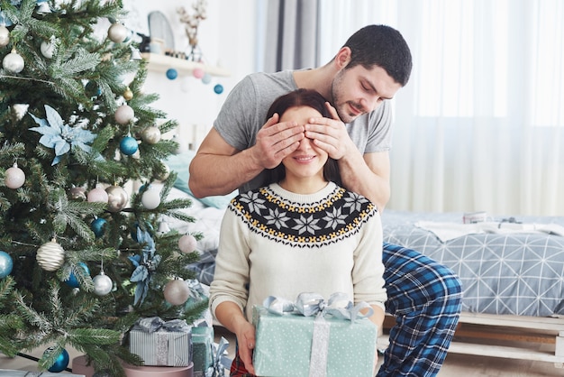 Jeune couple fête Noël. Un homme a soudainement présenté un cadeau à sa femme.