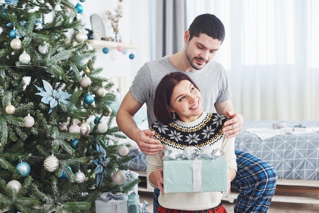 Jeune couple fête Noël. Un homme a soudainement présenté un cadeau à sa femme.