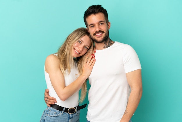 Jeune couple sur fond bleu isolé en riant