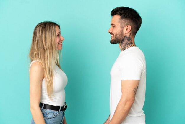 Jeune couple sur fond bleu isolé se regardant