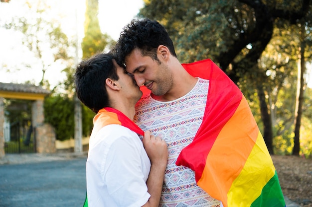 Jeune couple gay amoureux enveloppé dans un drapeau de fierté Heureux couple lgbt à un rendez-vous Hommes amoureux