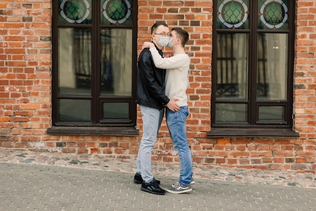 Jeune couple gay portant un masque médical étreignant la ville.