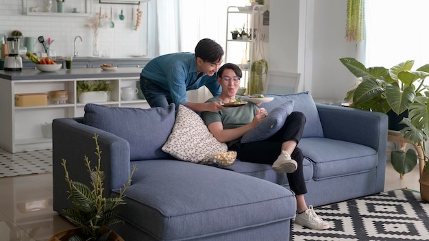 Jeune couple gay souriant ayant des aliments sains dans le salon à la maison LGBTQ et concept de diversité