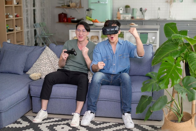 Jeune couple gay souriant jouant à des jeux vidéo dans le salon à la maison LGBTQ et diversité