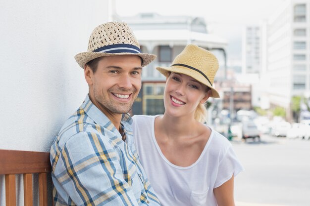 Jeune couple hanche assis sur un banc, souriant à la caméra