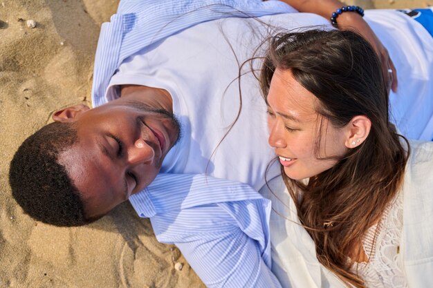 Jeune couple heureux allongé sur la vue de dessus de sable