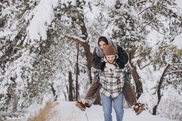 Photo un jeune couple heureux et amoureux s'amuse dans une forêt enneigée en hiver.