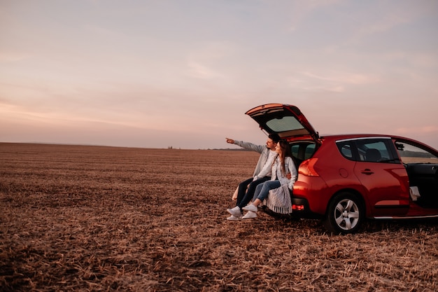 Jeune couple heureux assis sur leur nouveau coffre de voiture