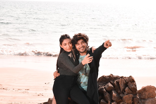 jeune couple heureux assis sur la plage modèle pakistanais indien