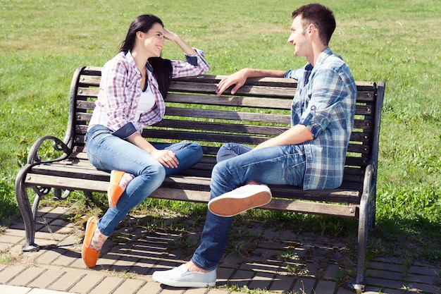 jeune couple heureux assis reposant sur un banc de parc