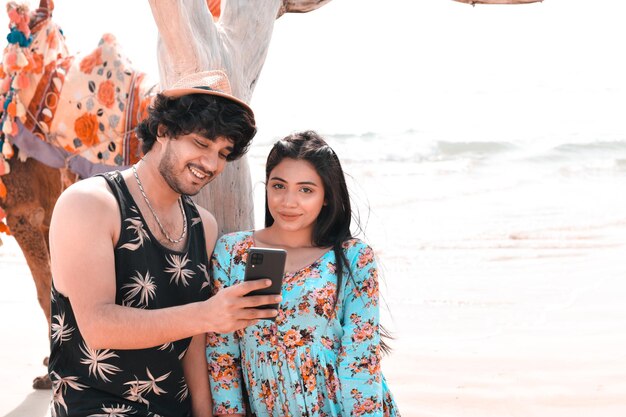 jeune couple heureux avant pose à l'aide de celphone à la plage modèle pakistanais indien