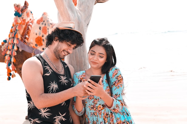 jeune couple heureux avant pose à l'aide de celphone à la plage modèle pakistanais indien