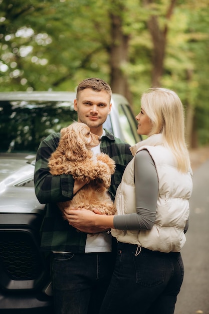 Un jeune couple heureux avec un chien dans la forêt.