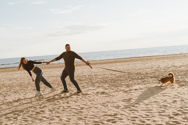 Jeune couple heureux et chien marchant sur la plage.