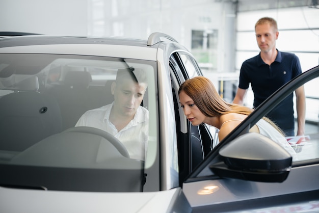 Un jeune couple heureux choisit une nouvelle voiture